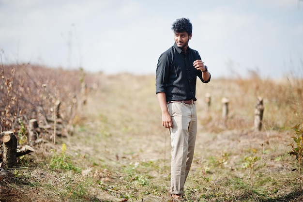 Homme indien en chemise noire et pantalon beige posé sur le terrain