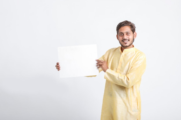 Homme indien tenant un tableau blanc debout sur un mur blanc