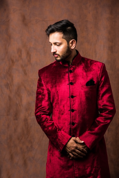 Homme indien en tenue traditionnelle OU kurta, vêtements de pyjama. Mannequin masculin en sherwani, posant ou debout sur fond grunge marron, mise au point sélective