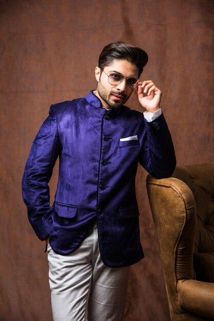 Photo homme indien en tenue traditionnelle ou kurta, vêtements de pyjama. mannequin masculin en sherwani, posant ou debout sur fond grunge marron, mise au point sélective