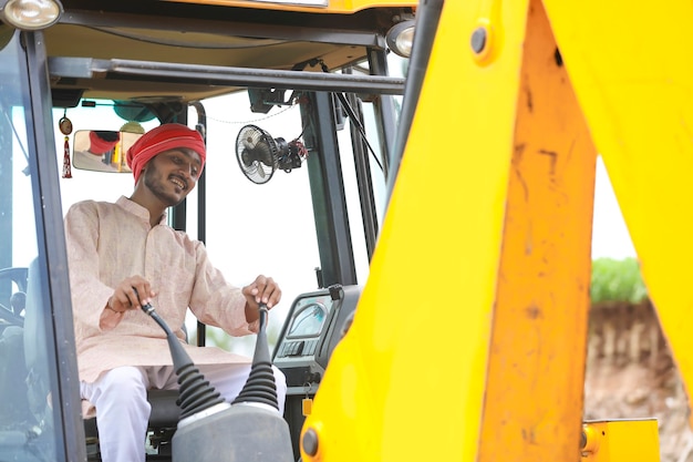 Homme indien travaillant avec un véhicule d'équipement lourd au chantier de construction.