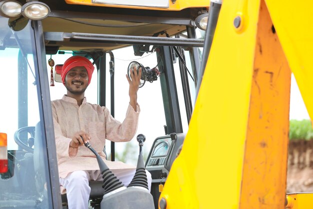 Homme indien travaillant avec un véhicule d'équipement lourd au chantier de construction.