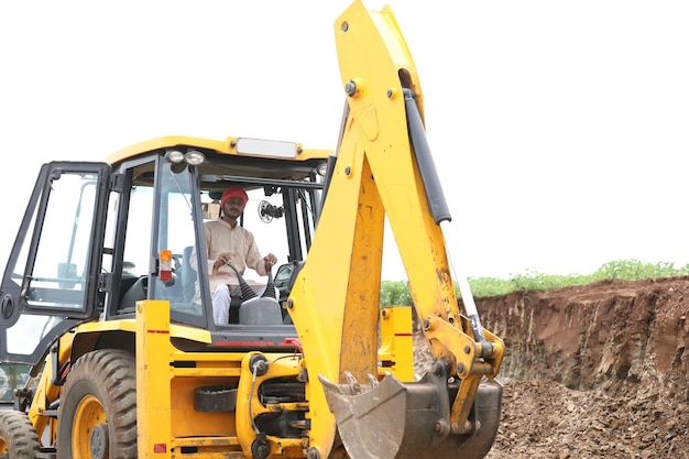 Homme indien travaillant avec un véhicule d'équipement lourd au chantier de construction.