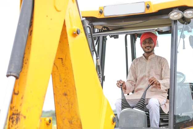 Homme indien travaillant avec un véhicule d'équipement lourd au chantier de construction.