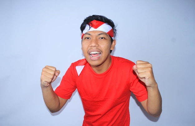 un homme indonésien excité a levé le poing pour célébrer le succès en t-shirt rouge du jour de l'indépendance de l'indonésie