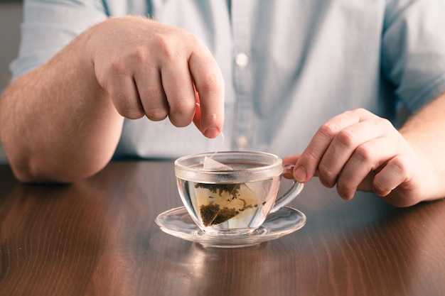 Homme, infusion, thé, sachet, verre, thé, table, bureau