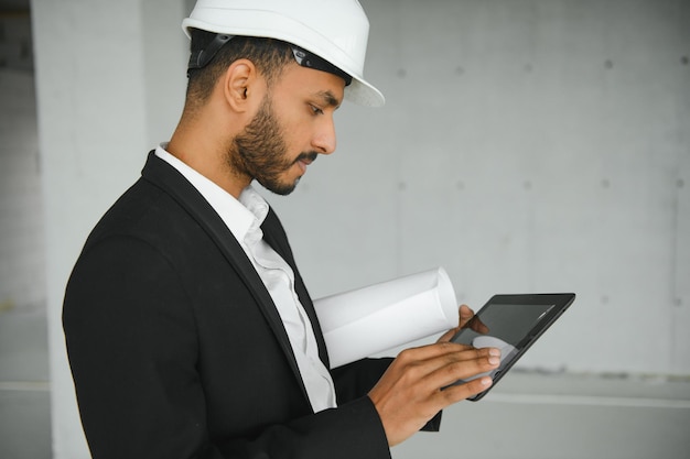 Homme ingénieur asiatique confiant utilisant une tablette pour vérifier et entretenir l'inspection dans la construction de maisons modernes Architecte travaillant avec un casque de sécurité blanc sur un chantier de construction