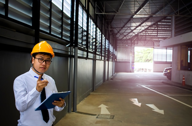 Homme ingénieur doigt pointant en usine avec note sur le bloc-notes