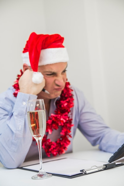 Photo homme inquiet calculant sur fond blanc. l'homme d'affaires célèbre joyeux noël et bonne année porte un chapeau de père noël