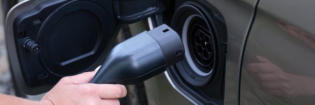 Homme insérant le câble électrique dans le plan rapproché de chargeur de voiture