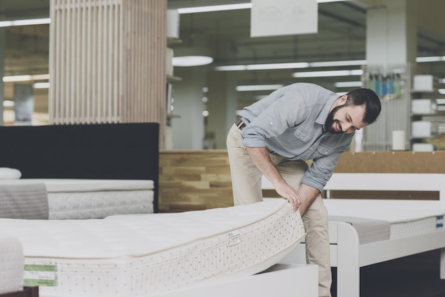 Un homme inspecte un matelas dans un magasin de matelas.