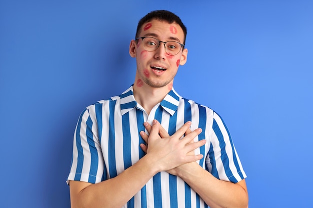 Homme inspiré avec des traces de baiser sur la joue avec les mains sur la poitrine