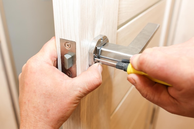 L'homme installe la poignée des portes Travaux de réparation Maintenance dans l'appartement