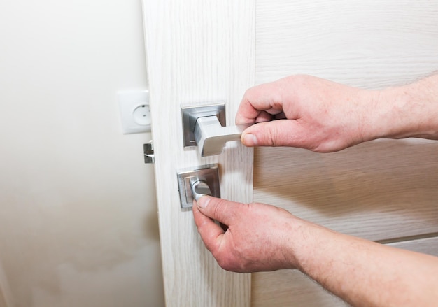 L'homme installe la poignée des portes Travaux de réparation Maintenance dans l'appartement