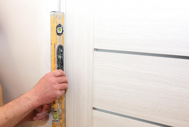 L'homme installe les portes. La réparation fonctionne avec un niveau à bulle. Entretien dans l'appartement.