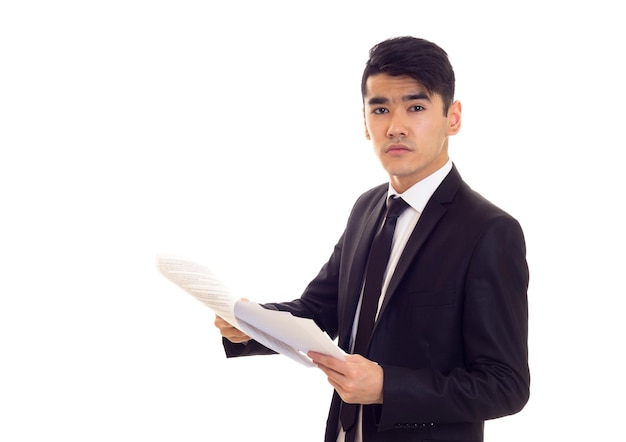 Homme intelligent aux cheveux noirs en chemise blanche et smoking noir avec une cravate noire tenant des papiers