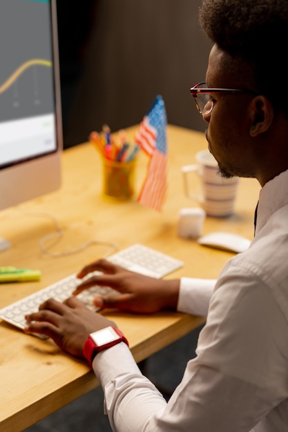 Homme intelligent qui travaille dur, assis devant l'ordinateur tout en tapant le texte dessus