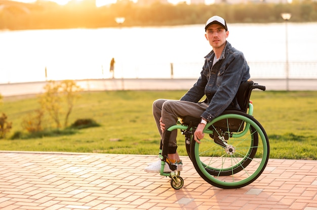 Homme invalide assis sur une chaise roulante et profitant d'une promenade en plein air photo de haute qualité