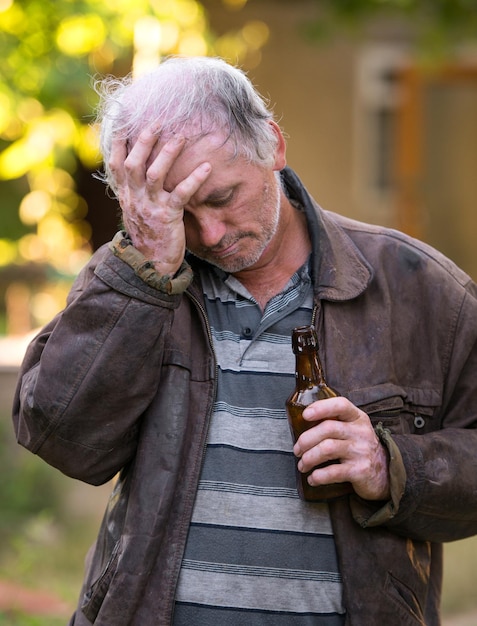 Homme ivre avec une bouteille de bière sur fond naturel