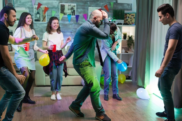 Homme ivre à la fête de ses amis faisant des pas de danse.