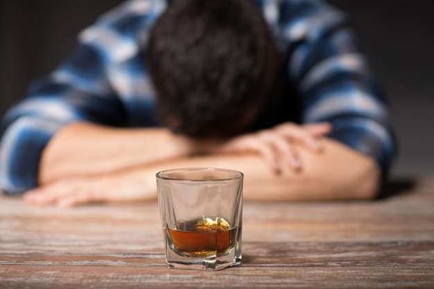 Photo homme ivre avec un verre d'alcool sur la table la nuit