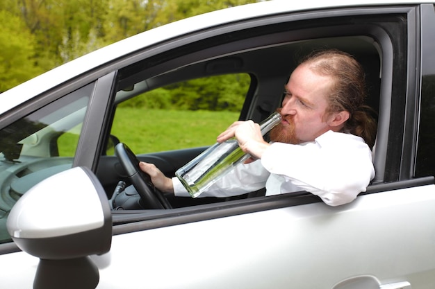 Homme ivre en voiture avec une bouteille d'alcool