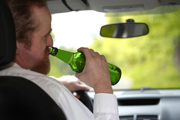 Homme ivre en voiture avec une bouteille de bière