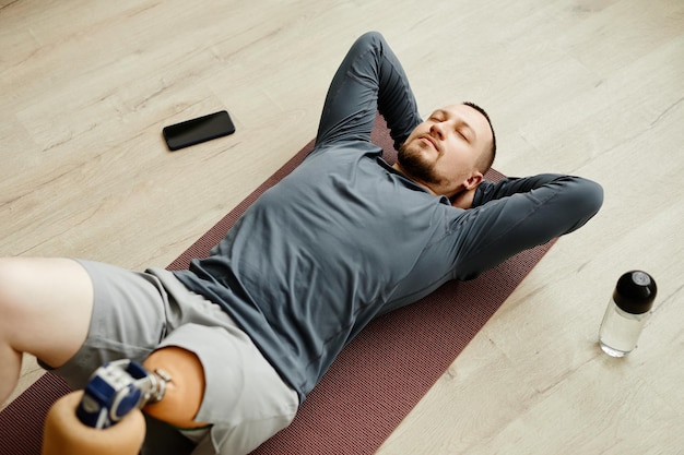 Homme avec jambe prothétique faisant des exercices à la maison