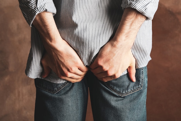 L'homme en jeans tient son cul sur le brun.