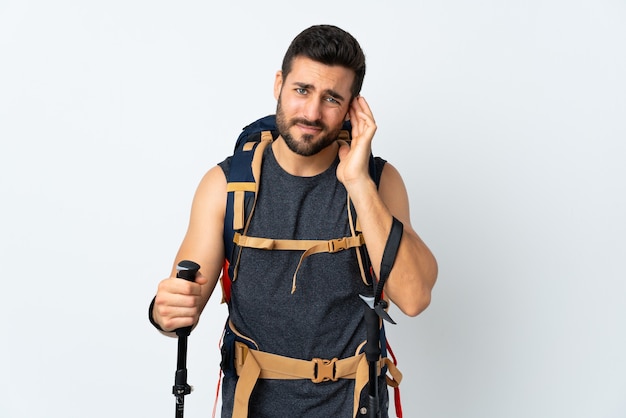 Homme jeune alpiniste avec un gros sac à dos et bâtons de randonnée isolés sur blanc malheureux et frustré par quelque chose. Expression faciale négative