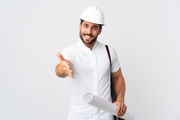 Homme jeune architecte avec casque et tenant des plans isolés sur blanc se serrant la main pour conclure une bonne affaire