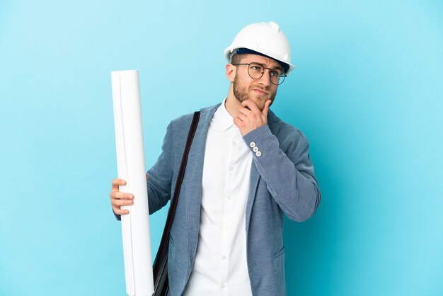 Homme jeune architecte avec casque et tenant des plans isolés