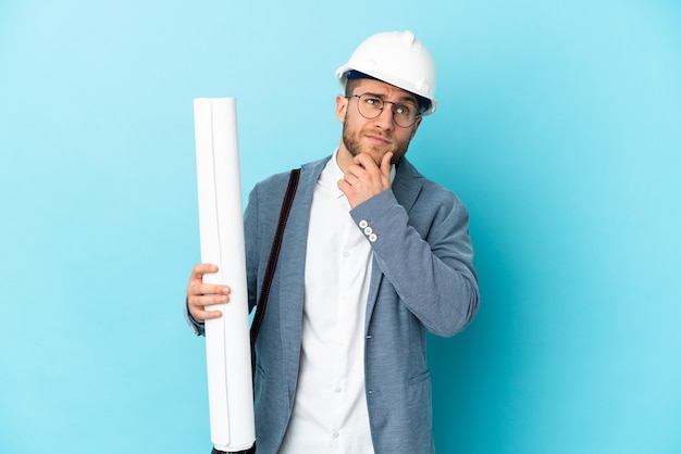 Homme jeune architecte avec casque et tenant des plans plus isolés et levant