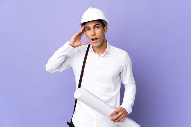 Homme jeune architecte isolé sur le mur avec une expression de surprise