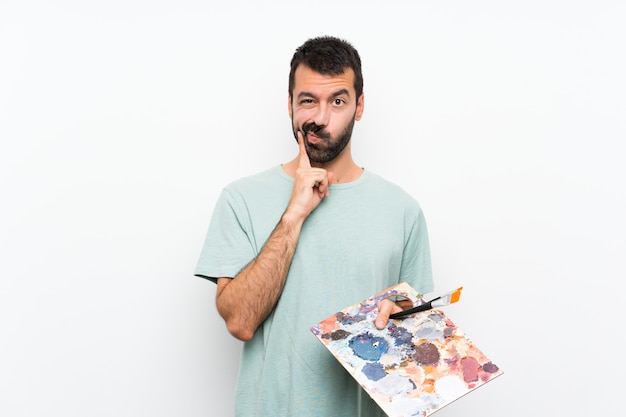 Homme jeune artiste tenant une palette sur un mur isolé