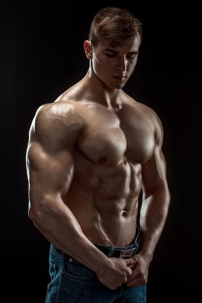 Homme jeune bodybuilder sur fond noir. Torse masculin. soulagement musculaire