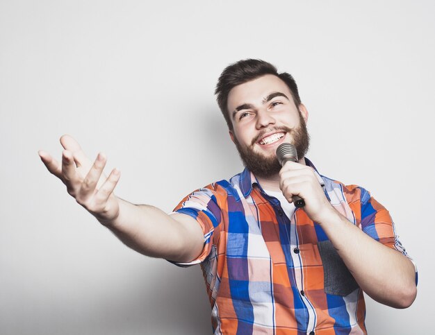 Homme jeune chanteur avec microphone sur fond gris