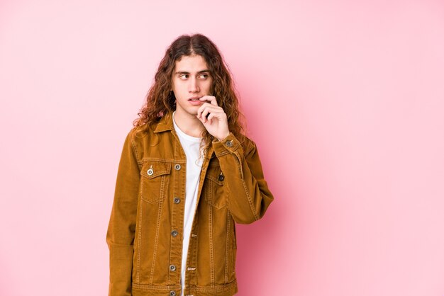 Homme jeune cheveux longs posant isolé pensée détendue sur quelque chose en regardant un espace de copie.