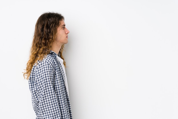 Homme jeune cheveux longs posant isolé regardant à gauche, pose de côté.