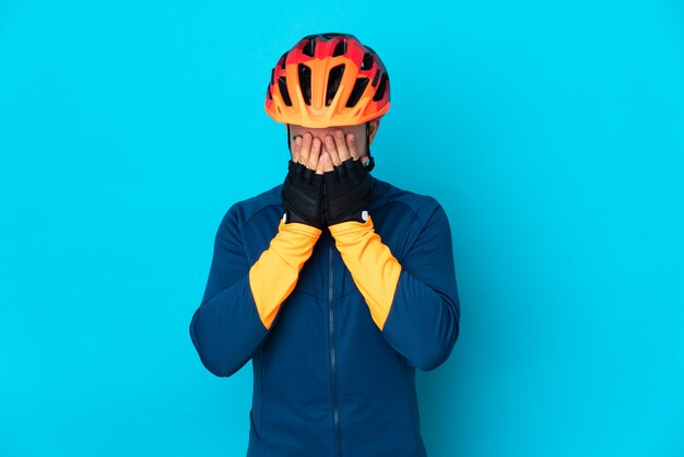 Homme jeune cycliste isolé sur fond bleu avec une expression fatiguée et malade