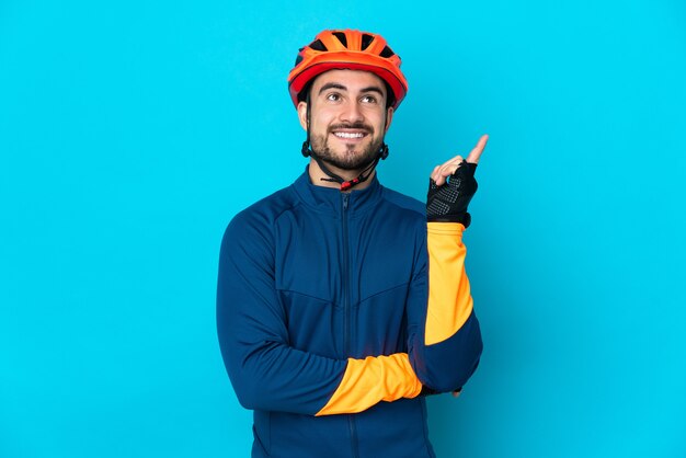 Homme jeune cycliste isolé sur fond bleu pointant vers le haut une excellente idée