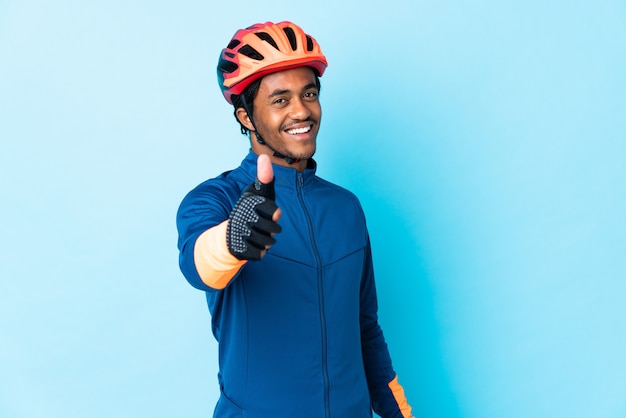 Homme jeune cycliste avec des tresses avec les pouces vers le haut parce que quelque chose de bien s'est passé