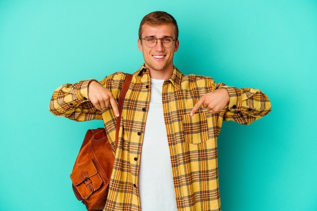 Homme jeune étudiant caucasien isolé sur des points bleus vers le bas avec les doigts, sentiment positif.