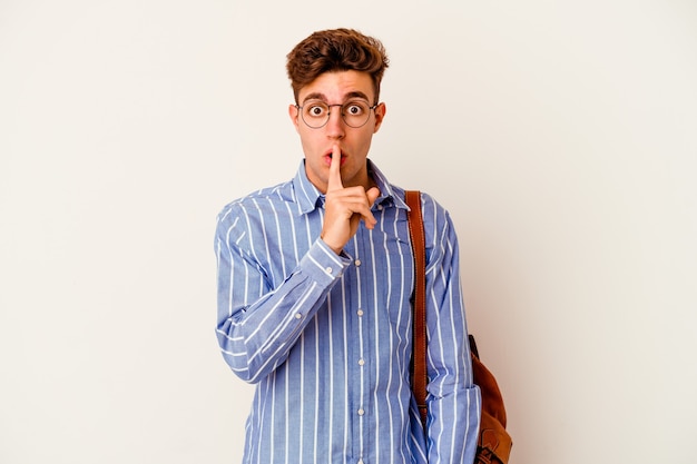 Homme jeune étudiant isolé sur un mur blanc gardant un secret ou demandant le silence.