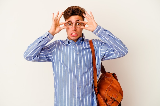 Photo homme jeune étudiant isolé sur un mur blanc en gardant les yeux ouverts pour trouver une opportunité de succès.