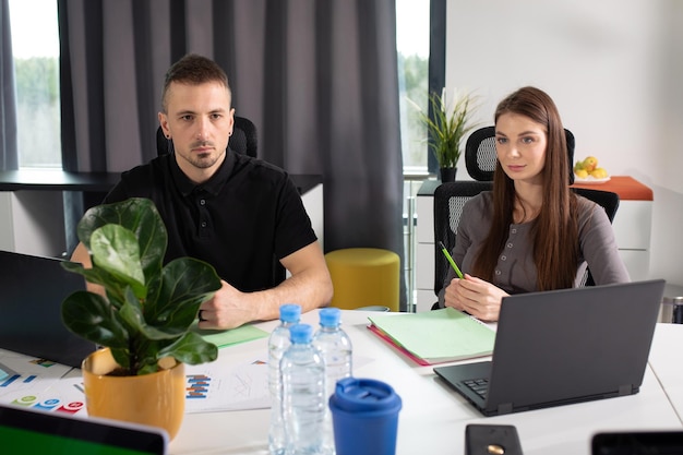 Un homme et une jeune femme collègues à la table discutent des plans de l'entreprise