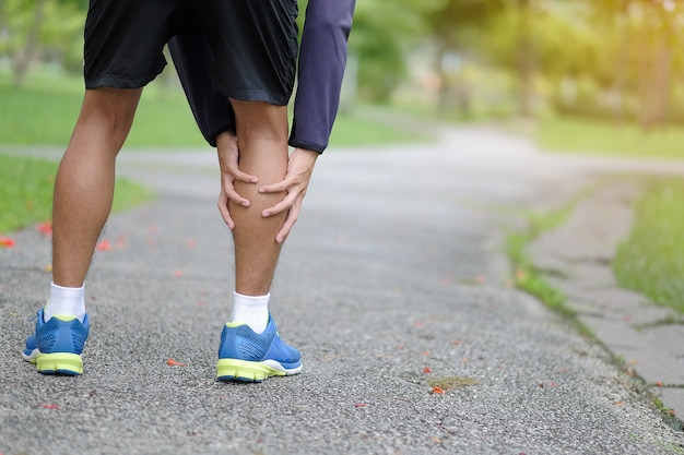 Homme jeune fitness tenant sa blessure à la jambe sportive