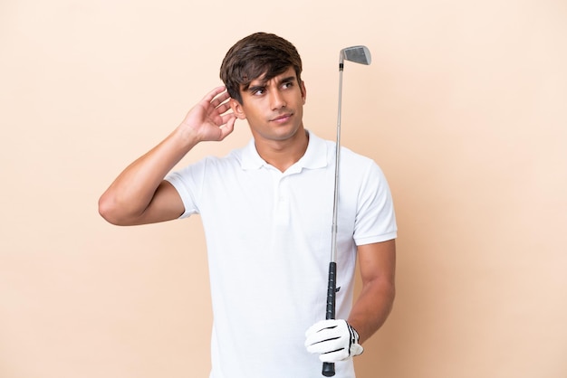 Homme jeune golfeur joueur isolé sur fond ocre ayant des doutes