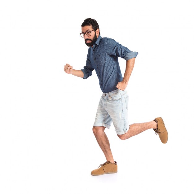 Homme jeune hipster courir vite sur fond blanc