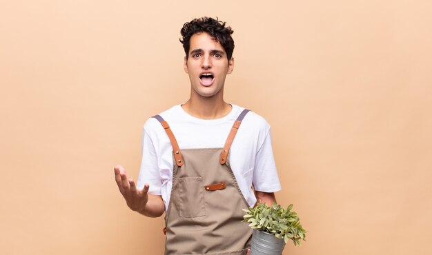 Homme jeune jardinier désespéré et frustré, stressé, malheureux et agacé, criant et hurlant